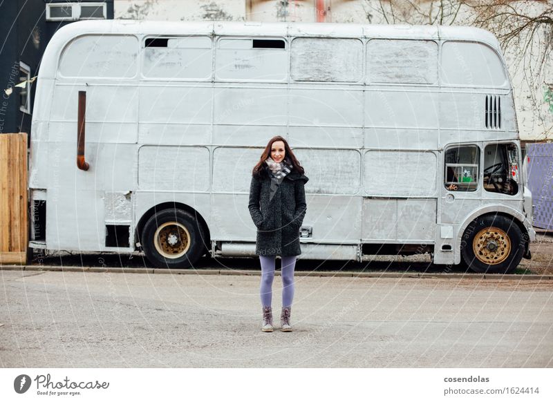 Junge Frau steht vor einem Bus Lifestyle Stil Winter feminin Jugendliche Erwachsene 1 Mensch 18-30 Jahre Stadt Straße Jacke Mantel Stiefel brünett Lächeln