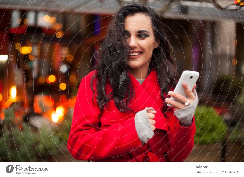 Frau in rotem Mantel mit Handy in der Hand, Smartphone, Stadtszene Telefon Lächeln Lifestyle Mädchen Mobile Person kalt Winter Technik & Technologie Zelle