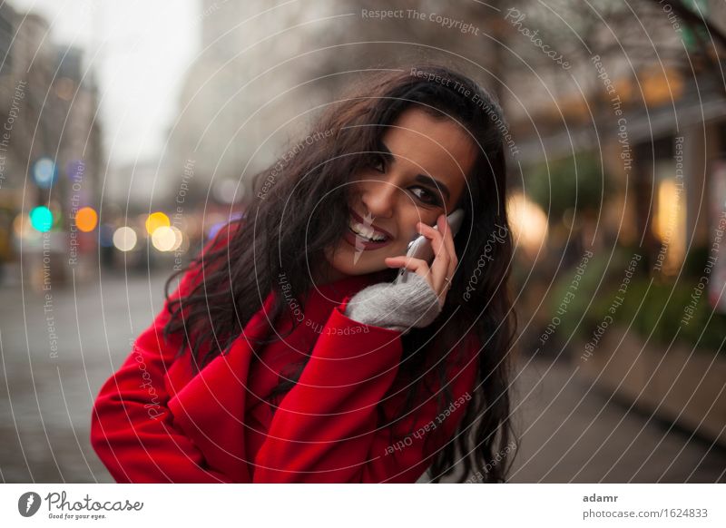 Schöne lächelnde Frau in rotem Mantel mit Mobiltelefon in der Hand, Smartphone, Stadtszene Telefon Lächeln Lifestyle Mädchen Mobile Person kalt Winter