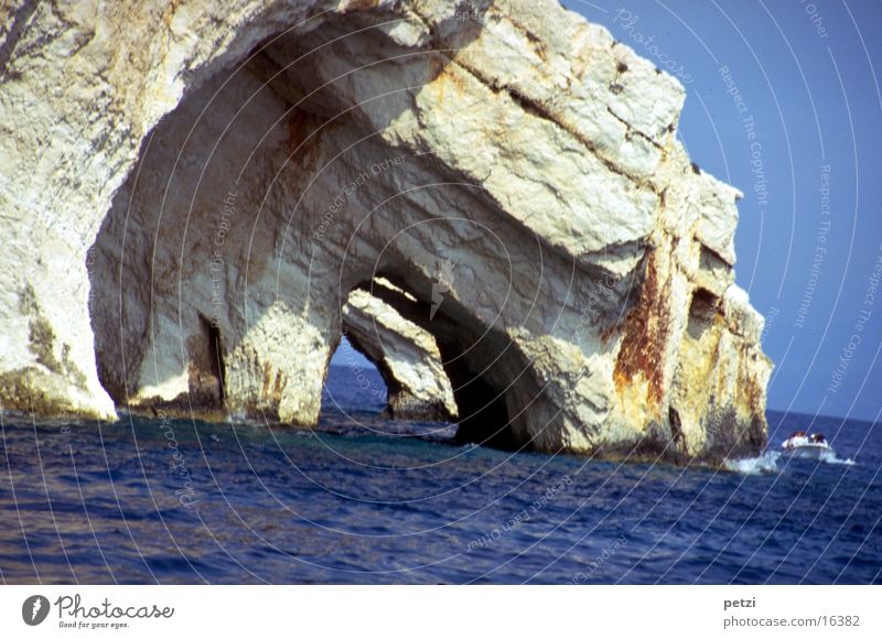 Höhlen im ionischen Meer Wasser Wolkenloser Himmel Sonne Sommer Felsen Wellen Mittelmeer Wasserfahrzeug blau grau Durchblick Gegensätze: fester Fels