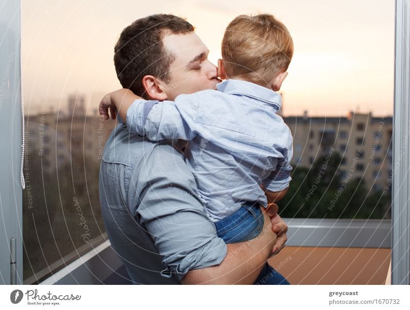 Dreißig Jahre alter Vater küsst seinen dreijährigen Sohn auf dem Balkon Lifestyle Freude Glück Gesicht Ferien & Urlaub & Reisen Sonne Kindererziehung Mensch