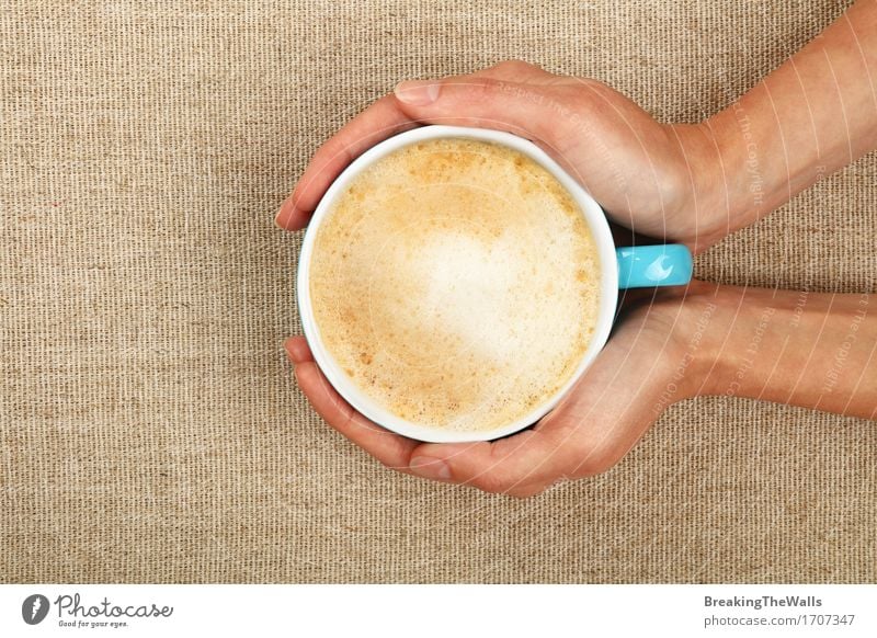 Zwei Frauenhände halten Lattecappuccino-Kaffeetasse auf Segeltuch Kaffeetrinken Getränk Heißgetränk Latte Macchiato Becher Junge Frau Jugendliche Erwachsene