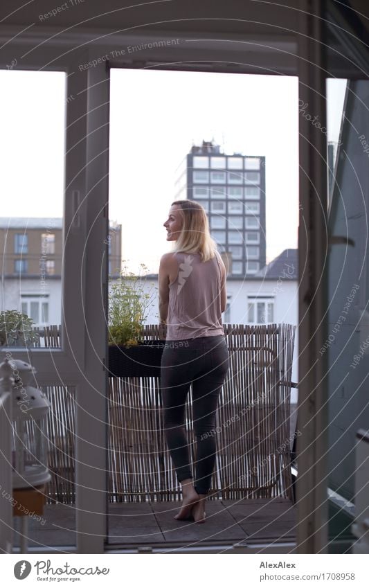 Wachstum in Balkonien I Häusliches Leben Balkonpflanze Balkontür Junge Frau Jugendliche 18-30 Jahre Erwachsene Landschaft Schönes Wetter Stadt Hochhaus T-Shirt