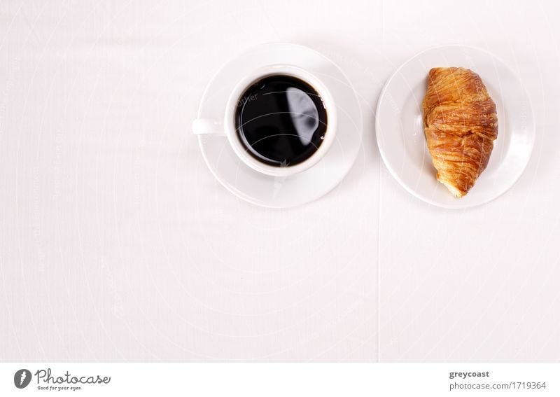 Draufsicht auf eine Tasse schwarzen Espressokaffee und ein frisch gebackenes Croissant zum Frühstück. Hoher Winkel Nahaufnahme Brot Marmelade Kaffee Teller heiß