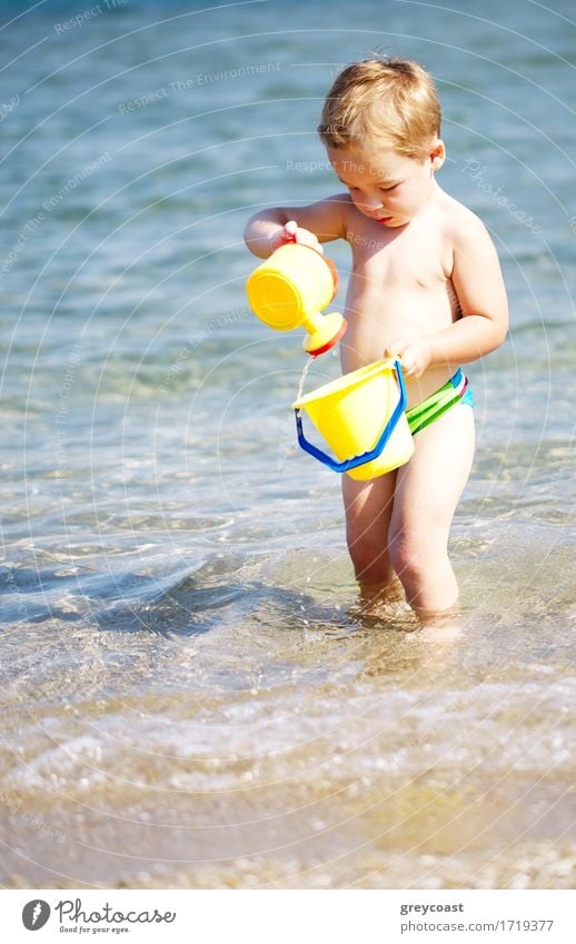 Adorable kleiner Junge spielt im Meer genießen die Sommersonne, wie er im Wasser paddelt seine Kunststoff-Spielzeug tragen Lifestyle Freude Glück schön