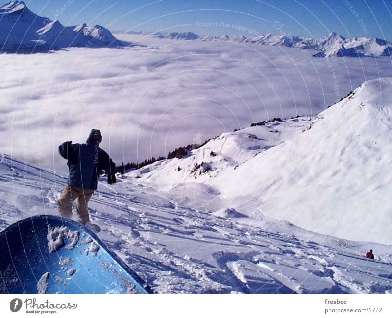 the ride Snowboard Sport Alpen Schnee Snowboarding Snowboarder Tiefschnee Pulverschnee über den Wolken Wolkendecke Tal Schneebedeckte Gipfel abwärts Spuren
