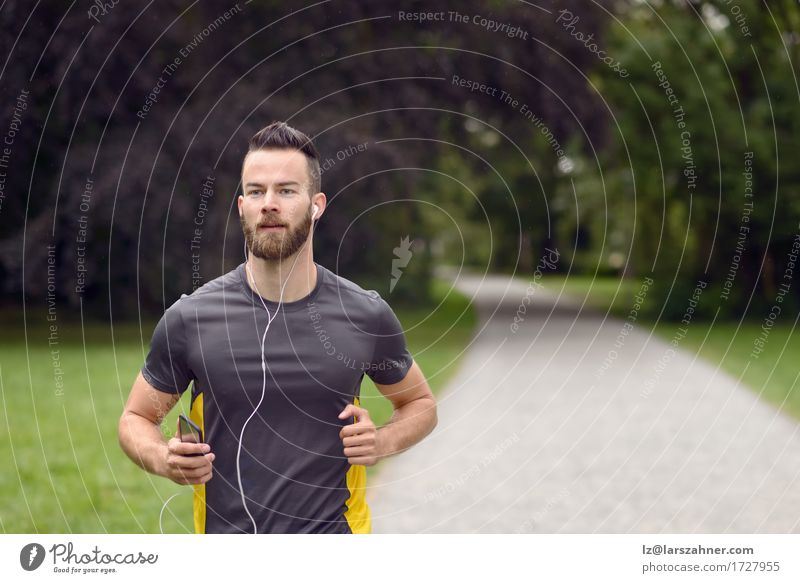 Geeigneter junger Mann, der in einem Park rüttelt Lifestyle Körper Gesicht Musik Sport Joggen Erwachsene 1 Mensch 18-30 Jahre Jugendliche Fitness hören Aktion