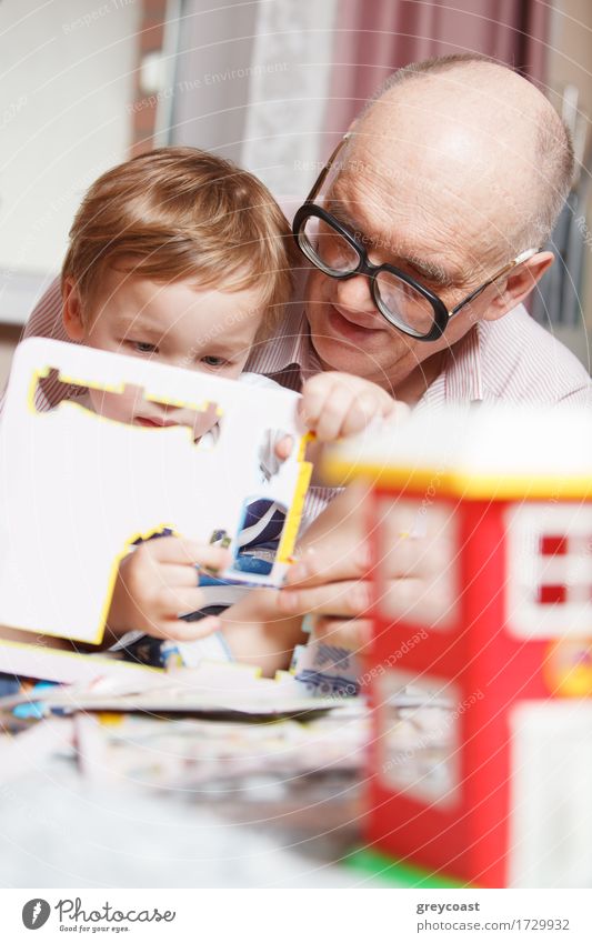 Großvater hilft seinem kleinen Enkel beim Lösen eines Puzzles. Glückliche Familie Zeit Freude Freizeit & Hobby Spielen Kind Mensch Junge Mann Erwachsene