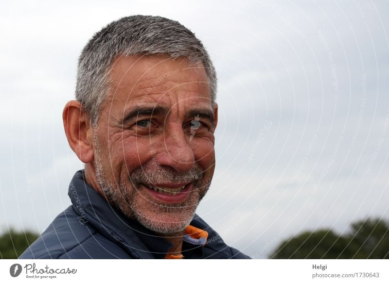 Porträt eines lächelnden Seniors mit grauen Haaren und grauem Bart vor grauem Himmel Mensch maskulin Mann Erwachsene Männlicher Senior Kopf Gesicht 1