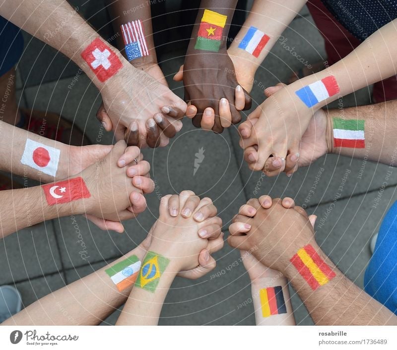 Nationen Hand in Hand - Menschen verschiedener Nationalitäten mit aufgemalten Flaggen halten sich an den Händen als Zeichen für Frieden und Solidarität