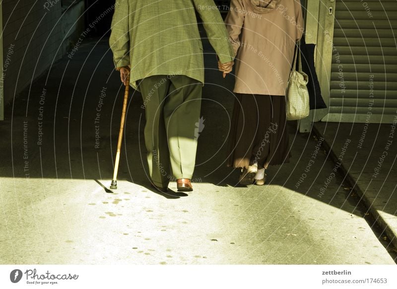 Paar Ehe Partnerschaft Romantik Liebe Zuneigung Zusammensein Hand in Hand Mann Frau alt Senior Ruhestand Tunnel dunkel Durchgang Stock Gehhilfe Spazierstock
