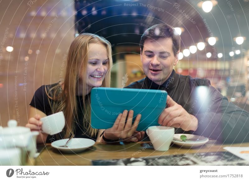 Glücklicher junger Mann und Frau trinken Kaffee beim Blick auf Tablet Tee Restaurant Sitzung Computer Junge Frau Jugendliche Junger Mann Geschwister Paar 2