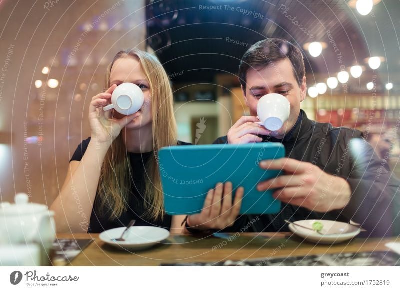 Mann und Frau trinken Kaffee, während sie ein Smart-Tablet halten Tee Restaurant Sitzung Computer Junge Frau Jugendliche Junger Mann Paar 2 Mensch 18-30 Jahre
