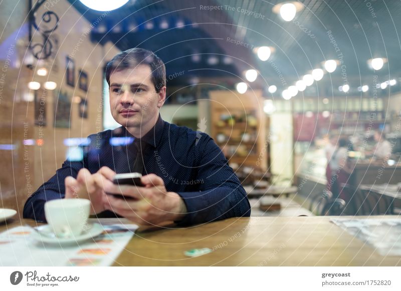 Mann am Tisch texting und trinken eine Tasse Kaffee im Cafe Restaurant Telefon PDA Homosexualität Junger Mann Jugendliche 1 Mensch 30-45 Jahre Erwachsene