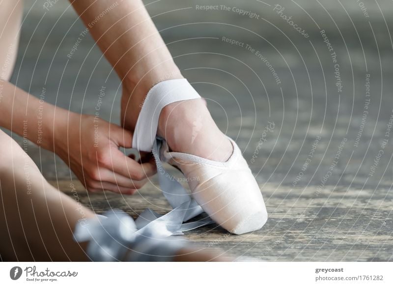 Nahaufnahme einer Ballerina beim Ausziehen der Ballettschuhe, die auf dem Boden im Studio sitzen elegant schön Studium Tanzschule Mädchen Jugendliche Fuß 1