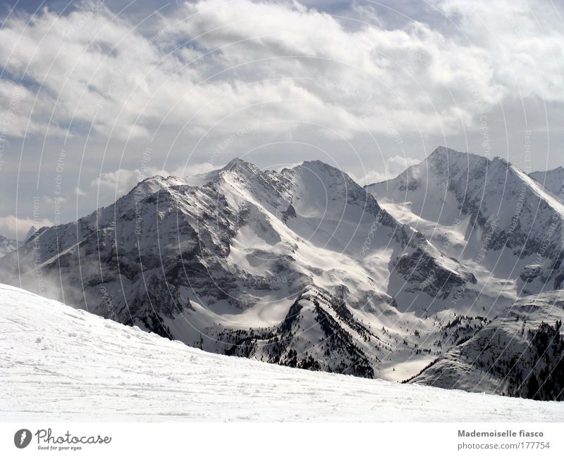 Skipiste und verschneite Berggipfel Winter Schnee Berge u. Gebirge Wintersport Wolken Alpen Schneebedeckte Gipfel hoch oben blau grau schwarz weiß Glück Idylle