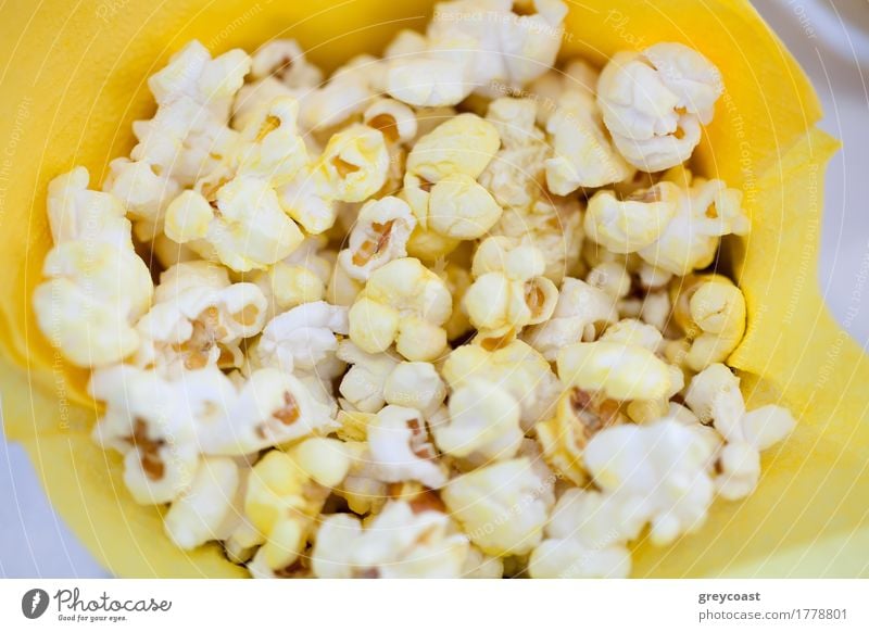 Hoher Winkel Nahaufnahme Schuss von leckeren Popcorn in gelben Papiertüte Kino Popkorn Lebensmittel Mahlzeit Tüte Snack geschmackvoll Film Hign-Winkel