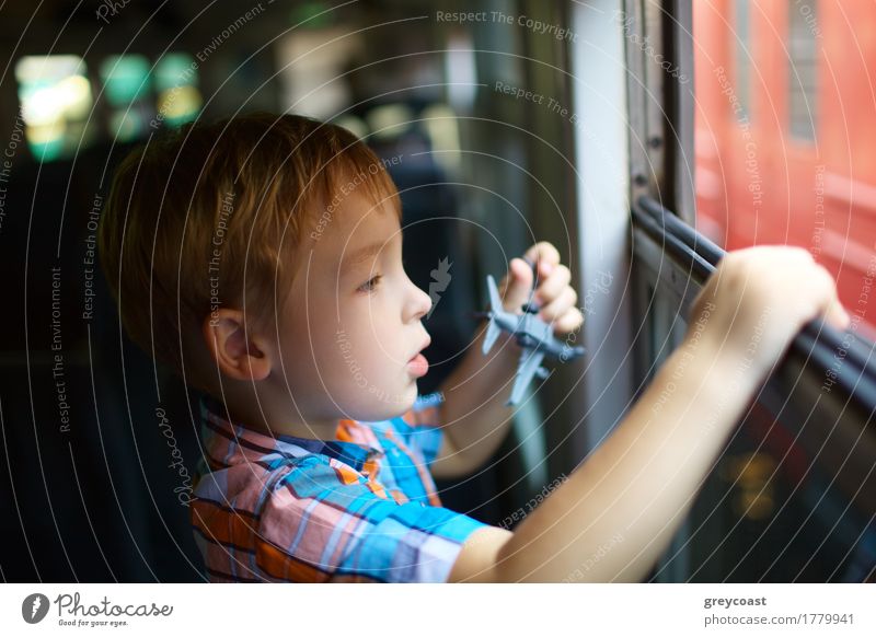 Neugieriger kleiner Junge mit Spielzeugflugzeug schaut aus dem offenen Zugfenster Ferien & Urlaub & Reisen Ausflug Kind Mensch 1 3-8 Jahre Kindheit Eisenbahn