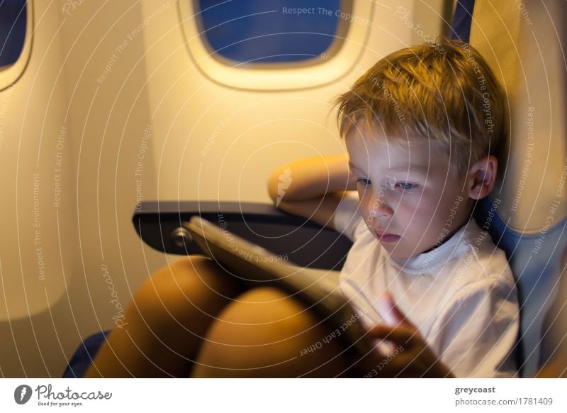 Kleiner Junge sitzt im Flugzeug und spielt auf Touchpad. Reisen mit dem Flugzeug Freude Freizeit & Hobby Spielen Ferien & Urlaub & Reisen Ausflug Kind Computer