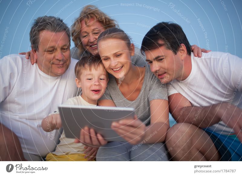 Glückliche große Familie mit guter Zeit zusammen. Großeltern und Eltern Blick auf das Pad Bildschirm während Junge mit ihm Freude Freizeit & Hobby Spielen