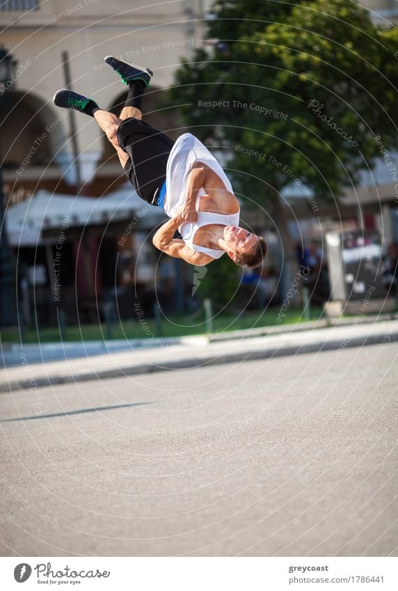 Junger Sportler, der seine akrobatischen Fähigkeiten bei einem Salto vorführt. Show in der Stadt Straße Lifestyle Sommer Mensch Mann Erwachsene Bewegung