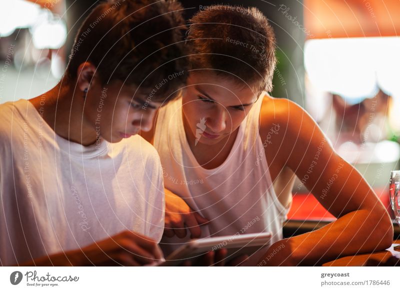Zwei männliche Teenager beim Surfen im Internet in einem Cafe. Unterhalten sich mit Elektronik Freizeit & Hobby Computer Mensch Mann Erwachsene Freundschaft