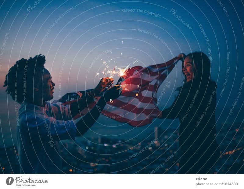 Afrikanischer Mann und Mädchen, die mit USA-Flagge und -sparkler feiern Lifestyle Freude Freiheit Feste & Feiern Frau Erwachsene Freundschaft 2 Mensch Stadt