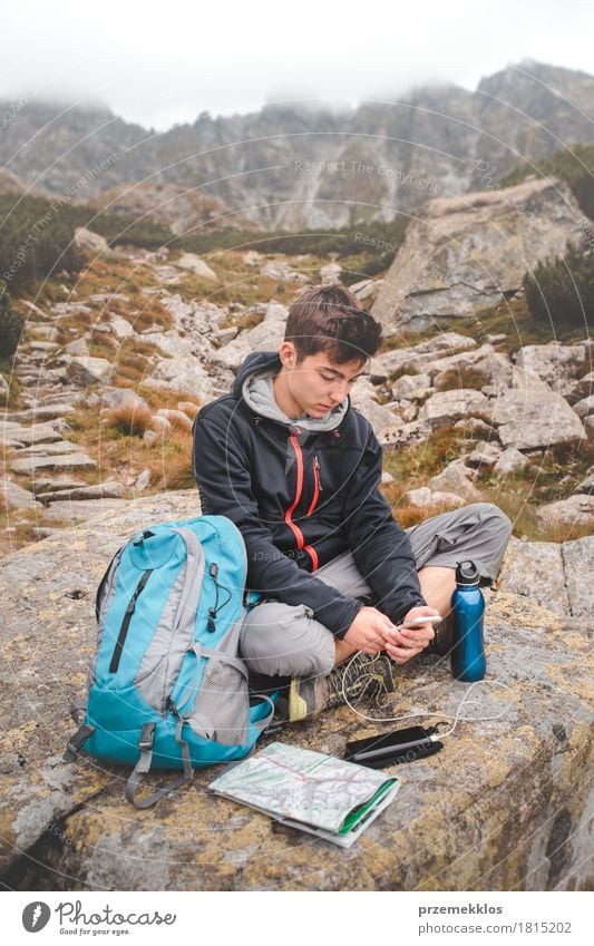 Junge, der auf einem Felsen stillsteht und einen Handy auflädt Flasche Lifestyle Freizeit & Hobby Ferien & Urlaub & Reisen Abenteuer Freiheit Sommer