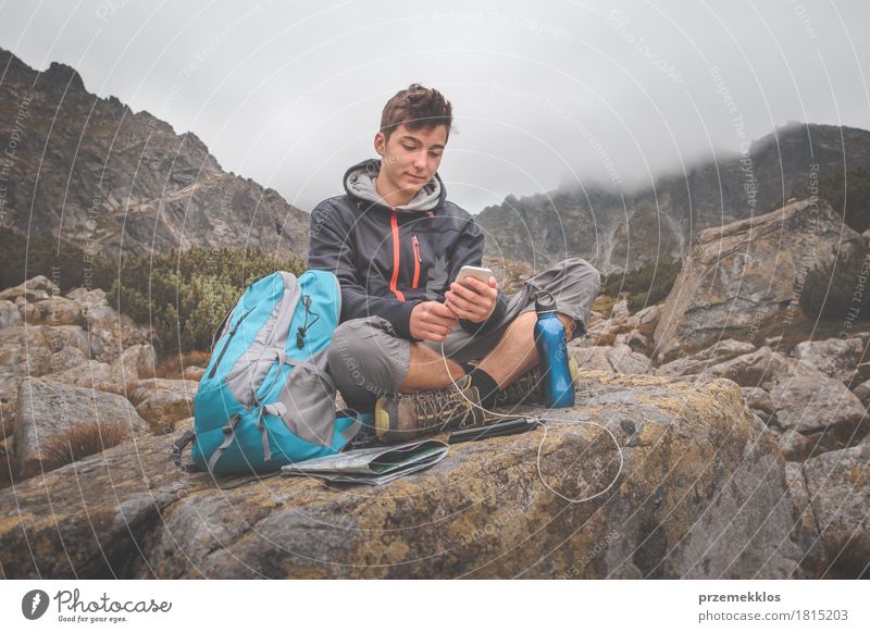 Junge, der auf einem Felsen stillsteht und einen Handy auflädt Flasche Lifestyle Freizeit & Hobby Ferien & Urlaub & Reisen Abenteuer Freiheit Sommer