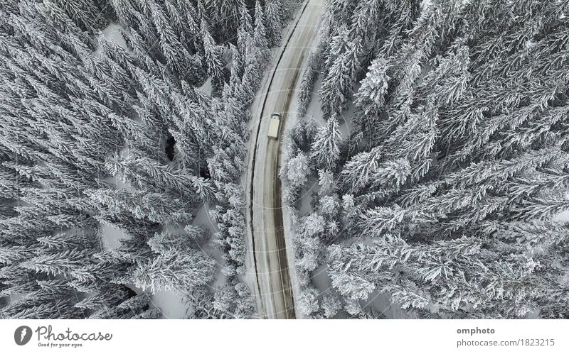 Luftaufnahme einer verschneiten und vereisten Winterstraße mit einem fahrenden Auto darauf Schnee Berge u. Gebirge Natur Landschaft Baum Wald Straße PKW