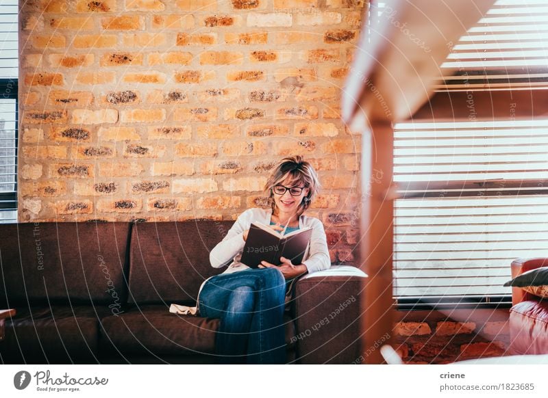 Kaukasische Frau, die ein Buch im Wohnzimmer im modernen Haus liest Lifestyle Freude Freizeit & Hobby lesen Häusliches Leben Wohnung Traumhaus lernen Büro