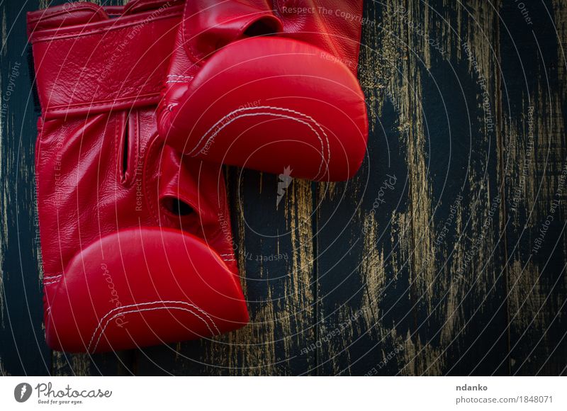 Rote lederne Boxhandschuhe für das Boxen auf einem schwarzen Hintergrund Sport Sportmannschaft Sportveranstaltung Erfolg Paar Leder Ring Handschuhe Holz Fitness