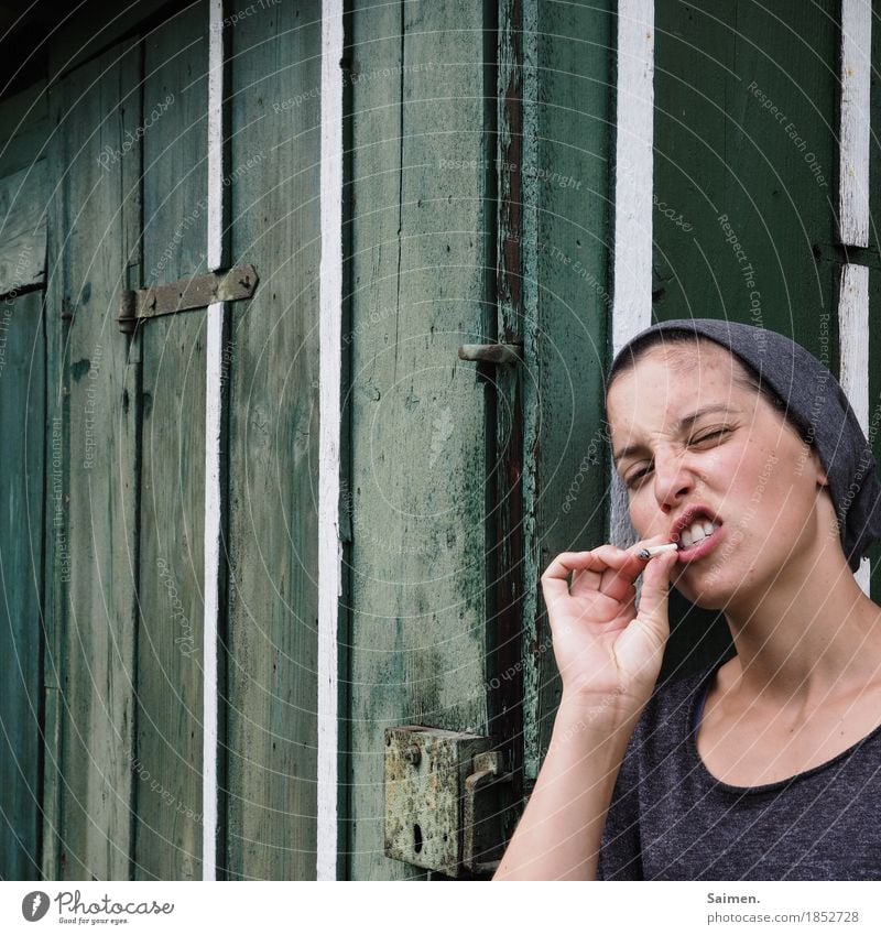 ... Mensch Frau Erwachsene 1 18-30 Jahre Jugendliche Rauchen Verachtung gereizt Feindseligkeit Aggression Mütze Zigarette Gesicht Holzwand Holzhütte gestreift
