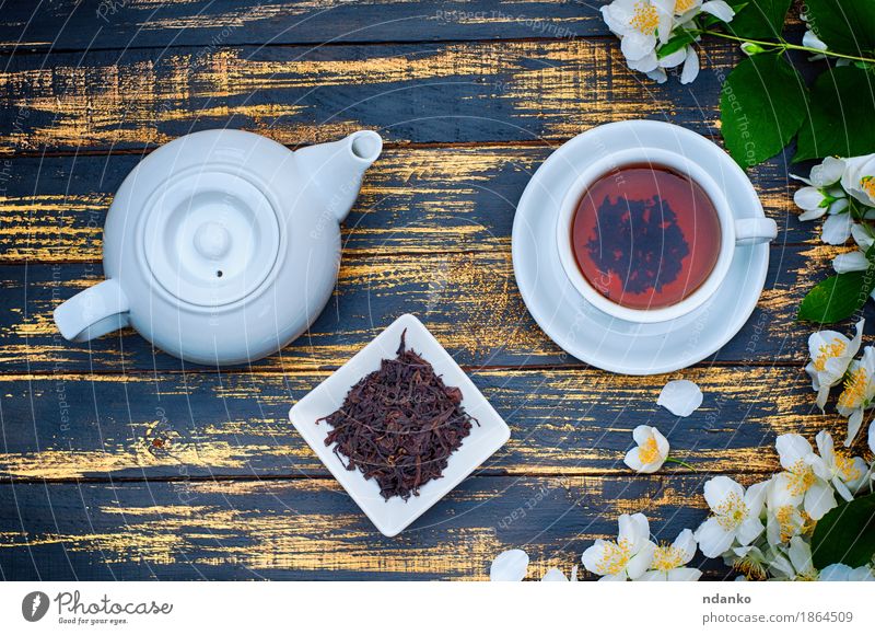 Schwarzer Tee in einer weißen Tasse und Untertasse und Jasminblüten Kräuter & Gewürze Frühstück Tisch Pflanze Blume Blatt Holz frisch heiß braun gelb grün
