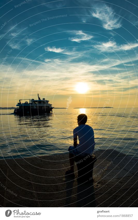 Junge auf Steg beobachtet abfahrendes Schiff bei Sonnenuntergang Abend wegfahren Einsamkeit Dämmerung Traurigkeit Gefühle Fähre Fernweh friedlich Küste