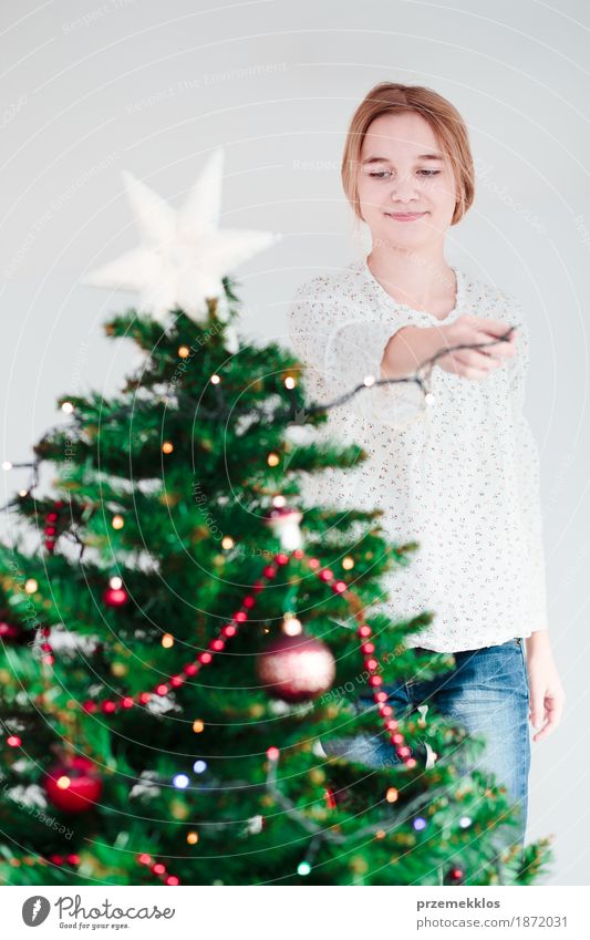 Junges Mädchen, das zu Hause Weihnachtsbaum mit Lichtern verziert Lifestyle Freude Dekoration & Verzierung Feste & Feiern Weihnachten & Advent Mensch