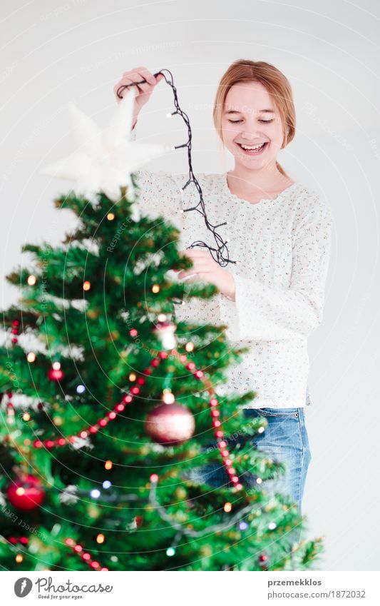 Junges Mädchen, das zu Hause Weihnachtsbaum mit Lichtern verziert Lifestyle Freude Dekoration & Verzierung Feste & Feiern Weihnachten & Advent Mensch