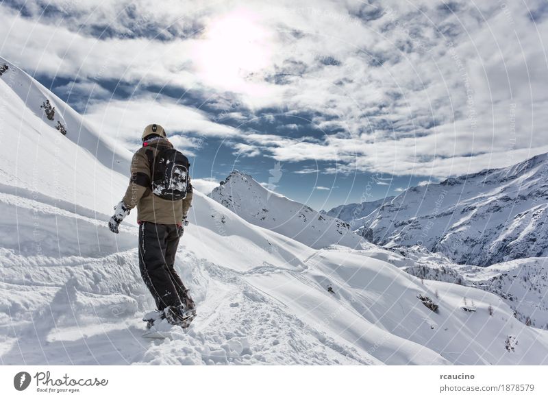 Snowboarder geht bergab über eine verschneite Berglandschaft. Ferien & Urlaub & Reisen Winter Schnee Berge u. Gebirge Sport Skifahren Junge Landschaft Himmel