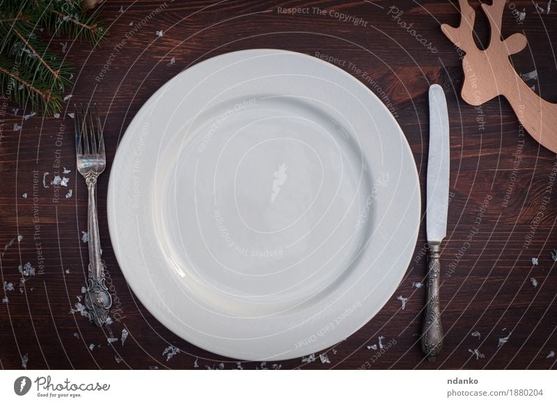 Weiße Platte mit silbernem Messer und Gabel auf brauner Holzoberfläche Frühstück Abendessen Festessen Geschirr Teller Winter Schnee Tisch Küche Restaurant Platz