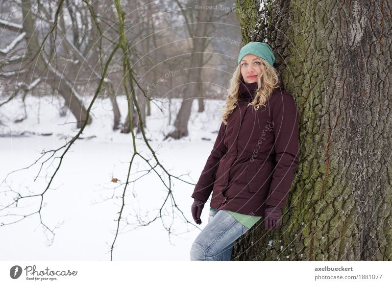 woman leaning against tree in winter landscape Lifestyle Winter Schnee Mensch feminin Frau Erwachsene 1 30-45 Jahre Natur Baum Park Wald Mode Jeanshose Jacke