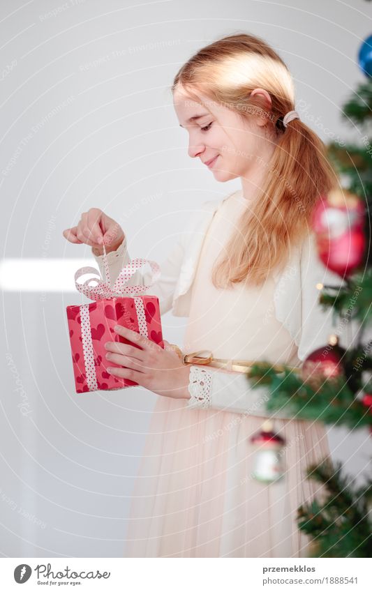 Glückliches Mädchen, welches das Weihnachtsgeschenk steht hinter einem Baum auspackt Lifestyle Feste & Feiern Weihnachten & Advent Kind Mensch 1 8-13 Jahre