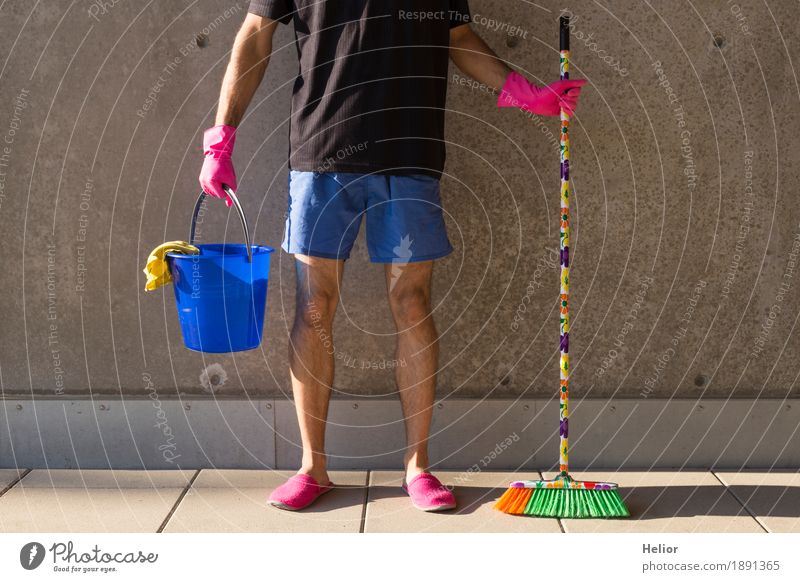 Ein Hausmann in rosaroten Hausschuhen und Putzutensilien Sommer maskulin Mann Erwachsene Beine 1 Mensch 30-45 Jahre Mauer Wand T-Shirt Besen Eimer Handschuhe