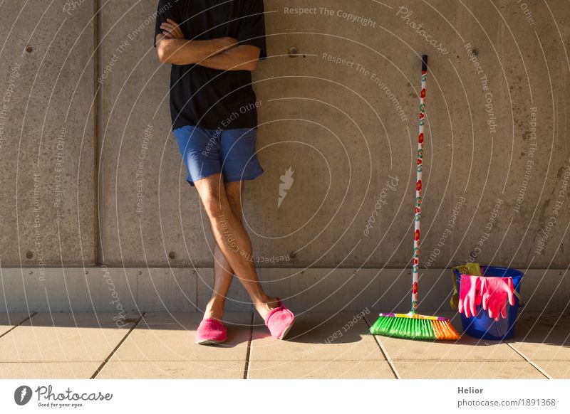 Ein Hausmann in rosaroten Hausschuhen und Putzutensilien Sommer maskulin Mann Erwachsene Körper 1 Mensch 30-45 Jahre Mauer Wand T-Shirt Besen Besenstiel Eimer
