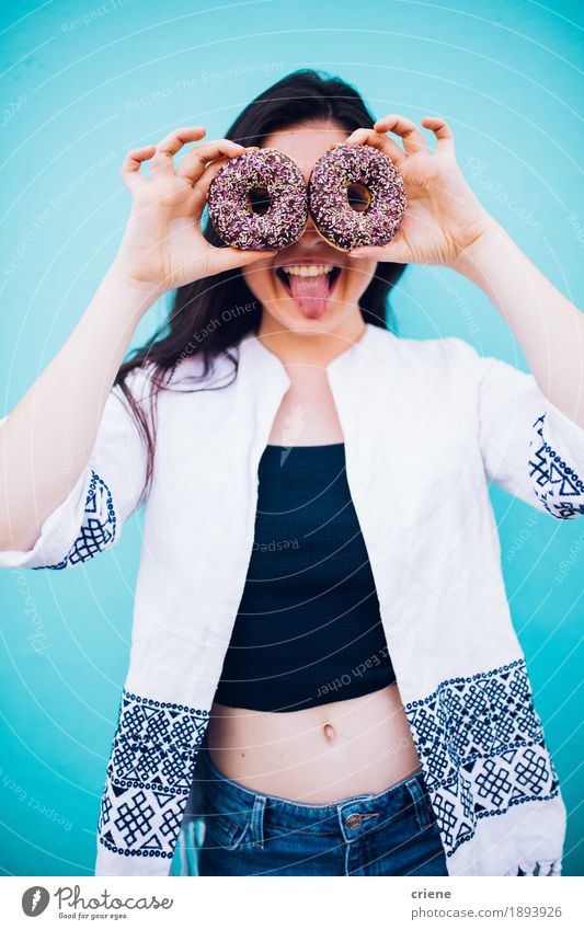 Mädchen, das Schokoladenschaumgummiringe vor ihrem Gesicht hält Lebensmittel Kuchen Dessert Süßwaren Essen Fastfood Lifestyle Freude Mensch Junge Frau