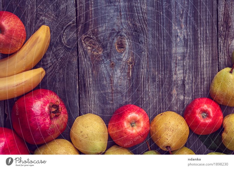 Bananen, Granatäpfel, Äpfel und Birnen auf einer grauen Holzoberfläche Frucht Apfel Bioprodukte Vegetarische Ernährung Garten Tisch Herbst frisch natürlich oben