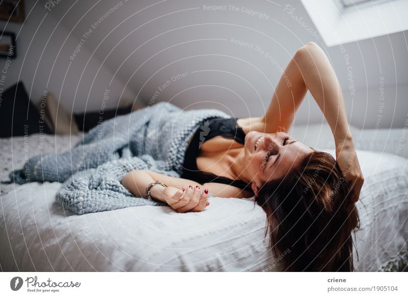 Das junge weibliche erwachsene Legen entspannt auf dem Bettlächeln Lifestyle Freude Glück ruhig Häusliches Leben Wohnung Haus Innenarchitektur Raum Schlafzimmer