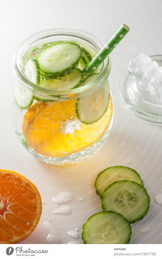 Ein Glas Erfrischungsgetränk mit Mandarine, Gurke und Strohhalm auf weißem Grund Getränk Frucht Gurkenscheibe trinken Trinkwasser Limonade Eiswürfel Trinkhalm
