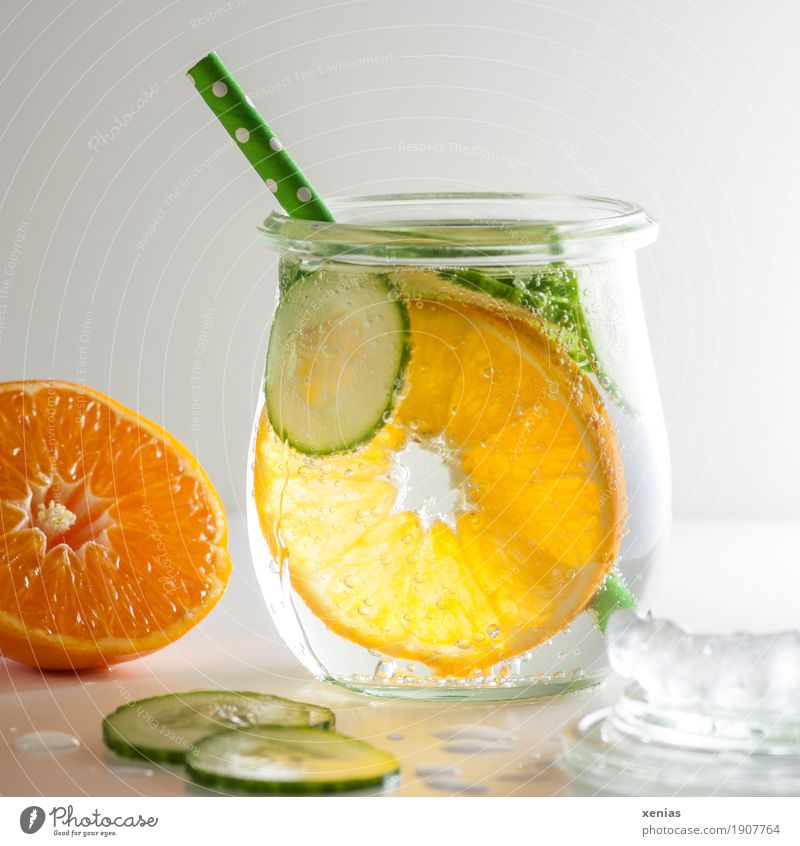 Kühles Erfrischungsgetränk mit Mineralwasser, Mandarine, Gurkenscheiben, Eiswürfel und grünem Trinkhalm Getränk trinken Trinkwasser Glas Gesundheit