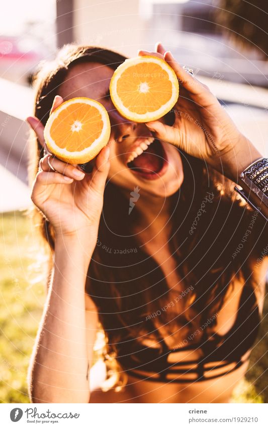 Junge Frauen, die Orangen vor ihrem Gesicht halten Lebensmittel Frucht Lifestyle Freude Erholung Sommer Sommerurlaub Sonne Sonnenbad Garten feminin Jugendliche