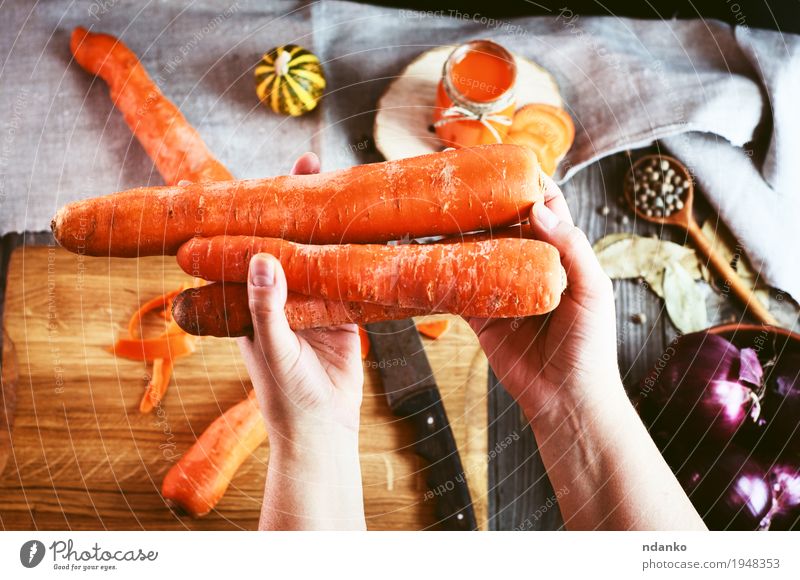 weibliche menschliche Hand, die drei große orange Karotte hält Lebensmittel Gemüse Kräuter & Gewürze Ernährung Vegetarische Ernährung Diät Getränk Saft Tisch